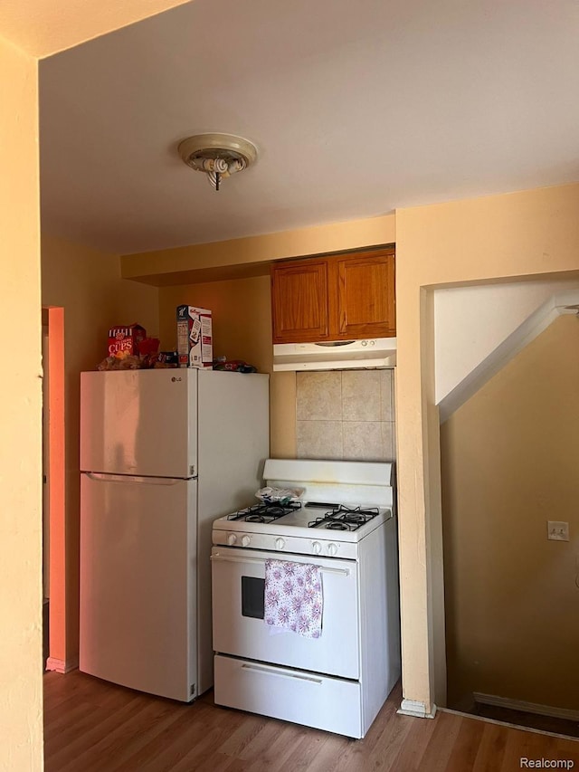 9910 Coyle St, Detroit, MI 48227 - kitchen featuring white appliances, under cabinet range hood, brown cabinets, and wood finished floors