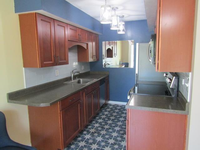 2024 Hamilton St, Okemos, MI 48864 - kitchen with a sink, appliances with stainless steel finishes, dark floors, a chandelier, and decorative light fixtures