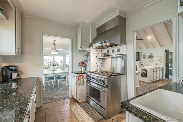 1786 Point St, Commerce Twp, MI 48382 - kitchen featuring wall chimney range hood, stainless steel stove, white cabinetry, tile patterned floors, and ornamental molding