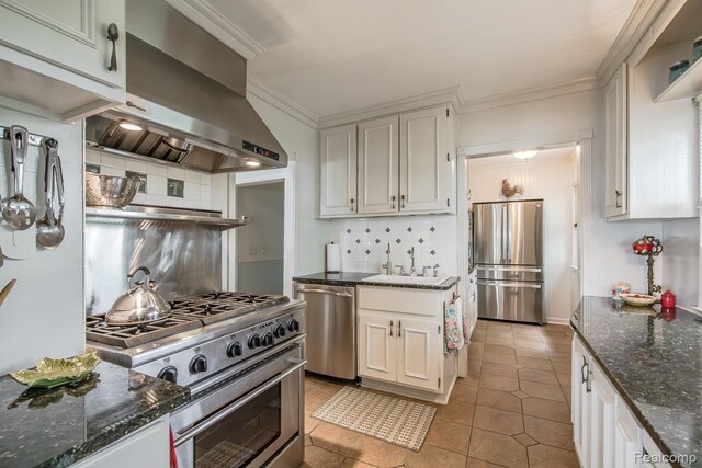 1786 Point St, Commerce Twp, MI 48382 - kitchen featuring appliances with stainless steel finishes, wall chimney range hood, tasteful backsplash, dark stone countertops, and light tile patterned floors