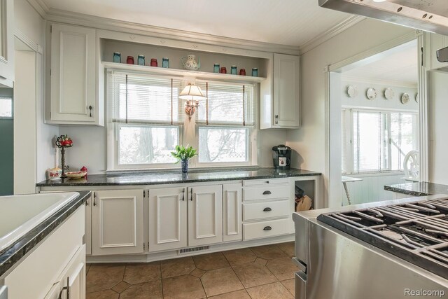 1786 Point St, Commerce Twp, MI 48382 - kitchen featuring stainless steel gas stove, dark tile patterned flooring, healthy amount of natural light, crown molding, and white cabinetry