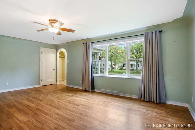 100 E 35th St, Holland, MI 49423 - empty room featuring arched walkways, a ceiling fan, baseboards, and wood finished floors