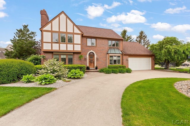 431 Meadowbrook Dr, Adrian, MI 49221 - tudor-style house with a chimney, brick siding, an attached garage, curved driveway, and a front lawn