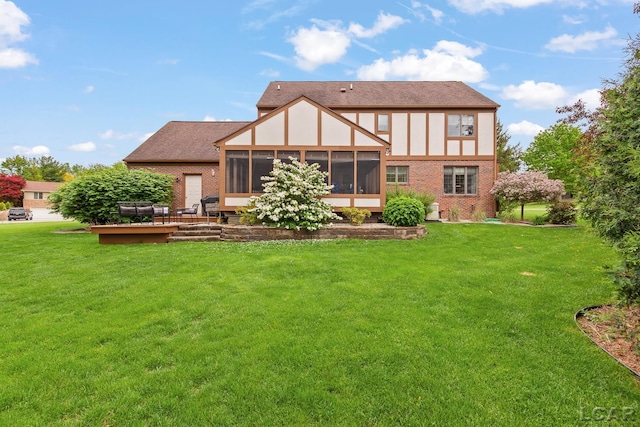 431 Meadowbrook Dr, Adrian, MI 49221 - back of property featuring a sunroom, brick siding, a lawn, and roof with shingles