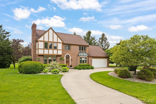 431 Meadowbrook Dr, Adrian, MI 49221 - tudor house featuring a chimney, driveway, a front yard, brick siding, and a garage