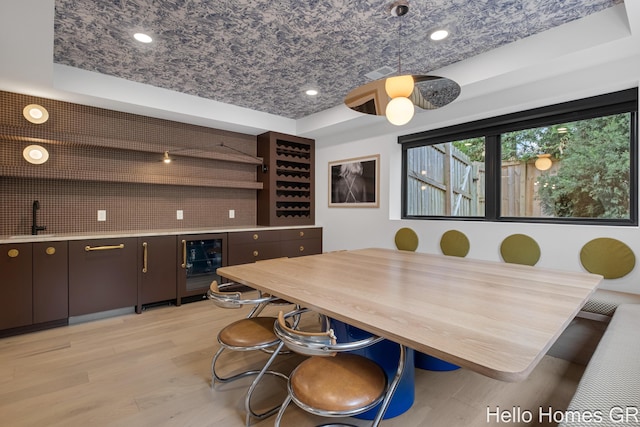 421 Manhattan Rd SE, Grand Rapids, MI 49506 - dining space with beverage cooler, wet bar, light wood-style flooring, a tray ceiling, and recessed lighting