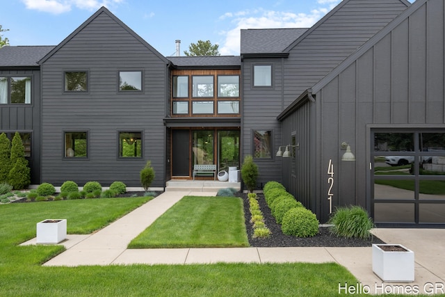 421 Manhattan Rd SE, Grand Rapids, MI 49506 - view of front of home with board and batten siding, a front yard, and a shingled roof