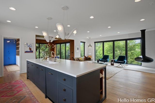 421 Manhattan Rd SE, Grand Rapids, MI 49506 - kitchen with a sink, light countertops, light wood-type flooring, recessed lighting, and a center island with sink