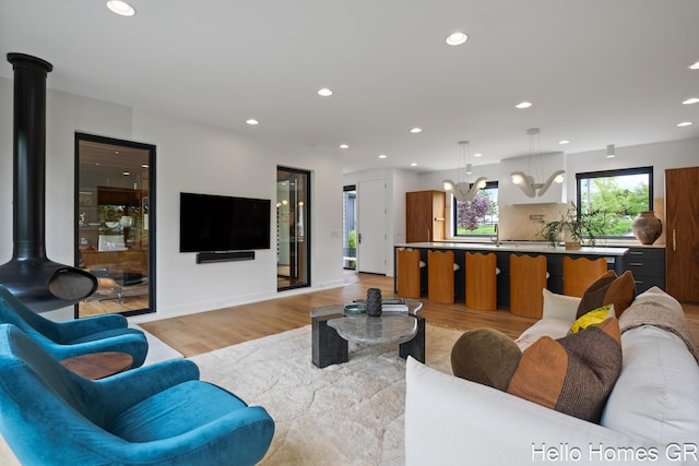 421 Manhattan Rd SE, Grand Rapids, MI 49506 - living area featuring light wood-style floors, recessed lighting, a chandelier, a wood stove, and baseboards
