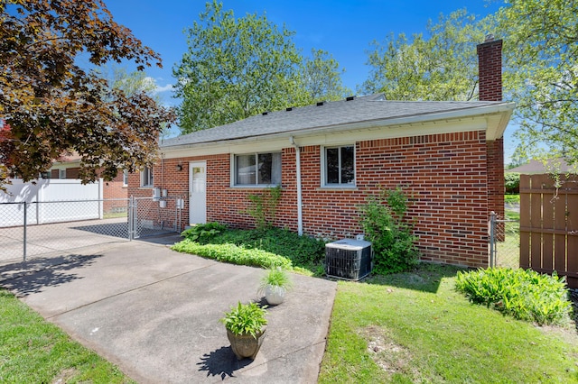9085 Brentwood St, Livonia, MI 48150 - view of front of property featuring central air condition unit, brick siding, a chimney, and a shingled roof