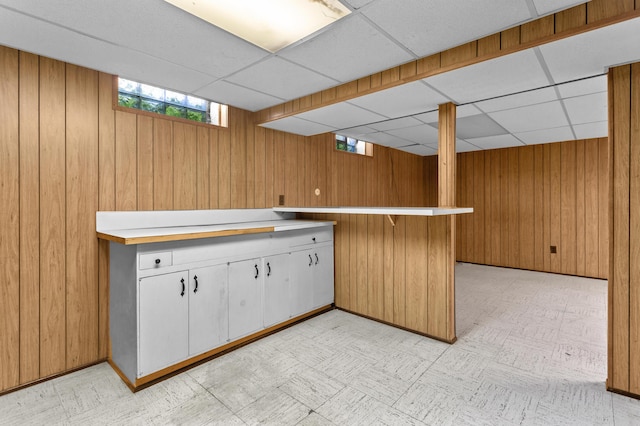 9085 Brentwood St, Livonia, MI 48150 - kitchen with wood walls, light flooring, a paneled ceiling, white cabinets, and light countertops