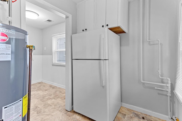 28506 Donnelly St, Garden City, MI 48135 - kitchen with freestanding refrigerator, water heater, white cabinetry, stone finish floors, and baseboards