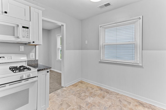 28506 Donnelly St, Garden City, MI 48135 - kitchen with white appliances, white cabinetry, baseboards, stone finish flooring, and a wainscoted wall