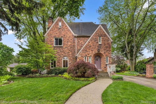 21975 Wildwood St, Dearborn, MI 48128 - english style home with a chimney, a front lawn, brick siding, and a shingled roof