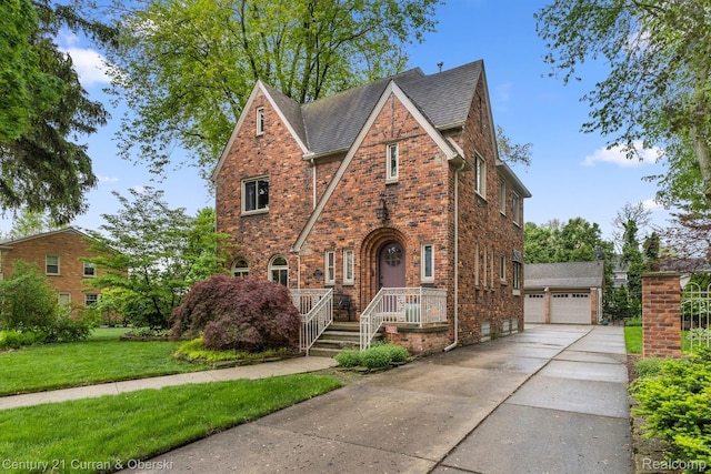 21975 Wildwood St, Dearborn, MI 48128 - english style home with a shingled roof, a front yard, brick siding, and a detached garage