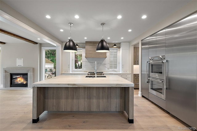 1626 Maryland Blvd, Birmingham, MI 48009 - kitchen featuring modern cabinets, double oven, a sink, a glass covered fireplace, and a spacious island