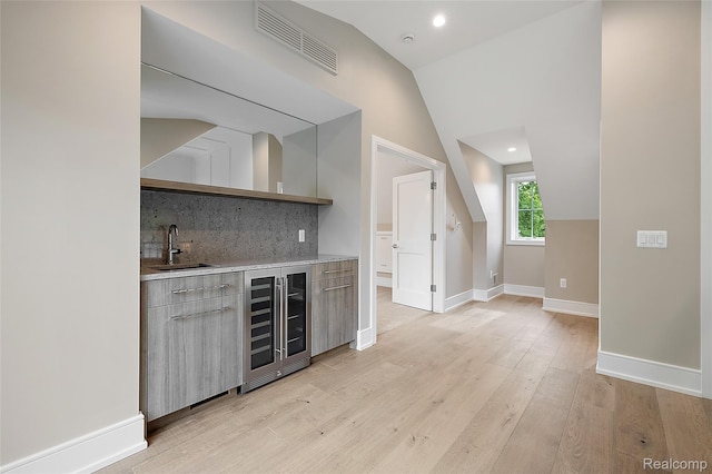1626 Maryland Blvd, Birmingham, MI 48009 - indoor wet bar featuring wine cooler, vaulted ceiling, tasteful backsplash, light wood finished floors, and baseboards