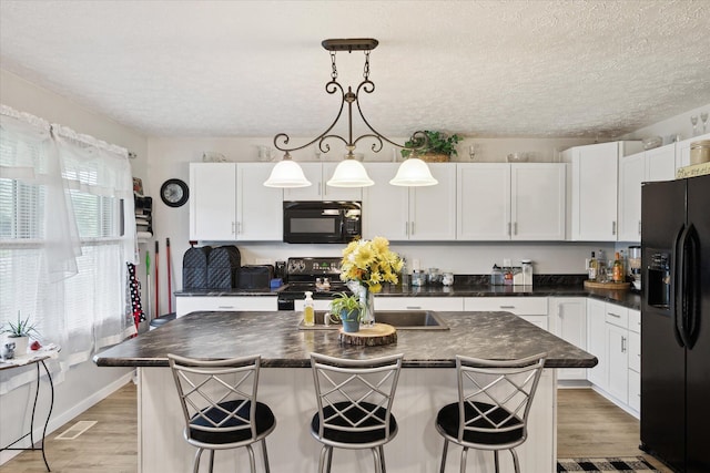 113 Diversy Dr, Brooklyn, MI 49230 - kitchen featuring black appliances, dark countertops, light wood-style flooring, a textured ceiling, and white cabinetry