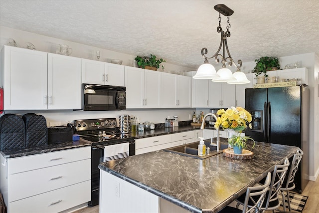 113 Diversy Dr, Brooklyn, MI 49230 - kitchen featuring black appliances, a sink, a textured ceiling, a center island with sink, and white cabinets