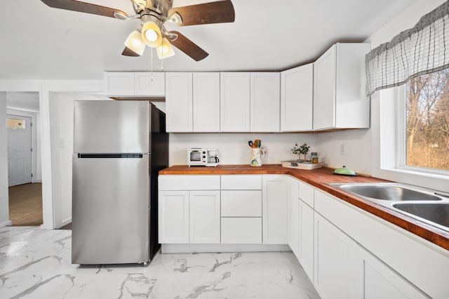 1585 Leeds Ave, Benton Harbor, MI 49022 - kitchen with freestanding refrigerator, wood counters, white cabinetry, ceiling fan, and light marble finish flooring
