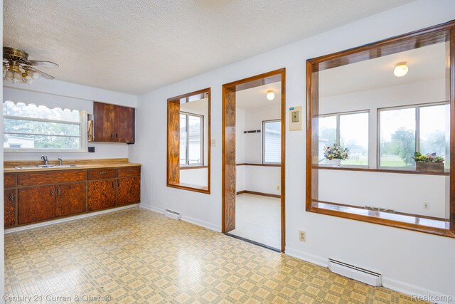 2548 Hearthside Dr, Ypsilanti, MI 48198 - kitchen featuring baseboard heating, light flooring, light countertops, a sink, and a ceiling fan