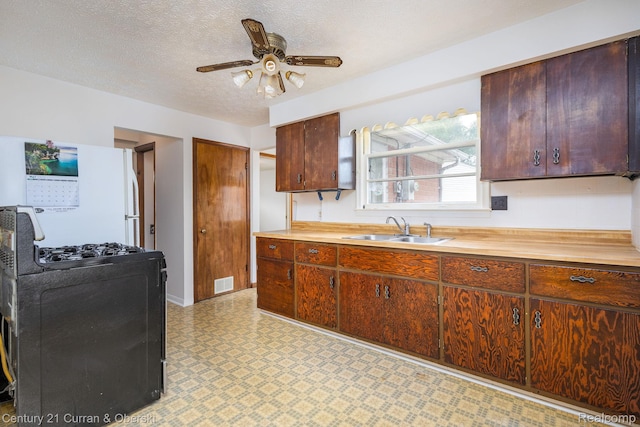 2548 Hearthside Dr, Ypsilanti, MI 48198 - kitchen with a sink, gas range oven, light floors, freestanding refrigerator, and ceiling fan