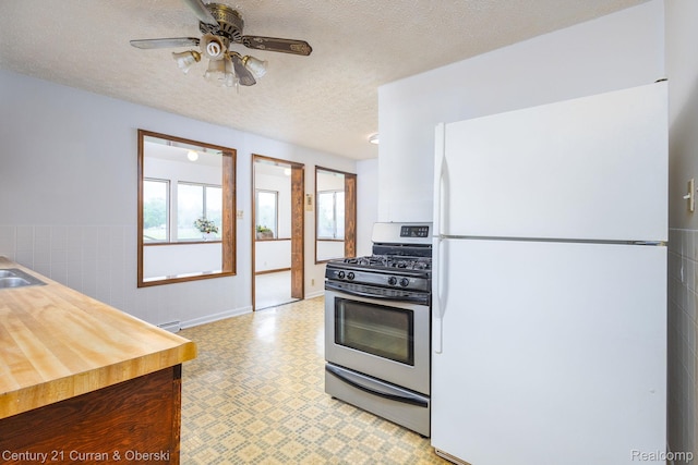 2548 Hearthside Dr, Ypsilanti, MI 48198 - kitchen featuring gas range, freestanding refrigerator, light flooring, a textured ceiling, and a ceiling fan