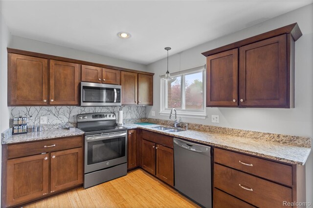 2375 Mulberry Sq Unit 69, Bloomfield Hills, MI 48302 - kitchen featuring appliances with stainless steel finishes, a sink, backsplash, light wood finished floors, and light stone counters