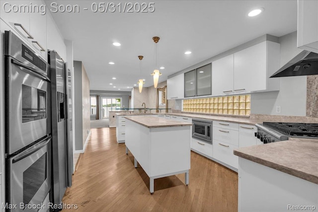 2222 Garland St, Sylvan Lake, MI 48320 - kitchen featuring appliances with stainless steel finishes, a peninsula, modern cabinets, light wood-style flooring, and white cabinetry