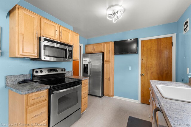 3135 Raymond Ave, Dearborn, MI 48124 - kitchen featuring stainless steel appliances, light brown cabinetry, a sink, light floors, and baseboards
