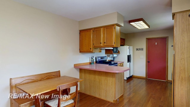 5475 George St, Saginaw, MI 48603 - kitchen featuring electric stove, dark wood-style flooring, white fridge with ice dispenser, and a peninsula