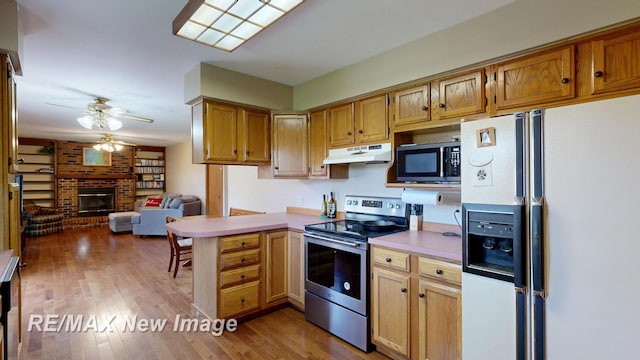 5475 George St, Saginaw, MI 48603 - kitchen featuring electric stove, white fridge with ice dispenser, under cabinet range hood, a fireplace, and a ceiling fan