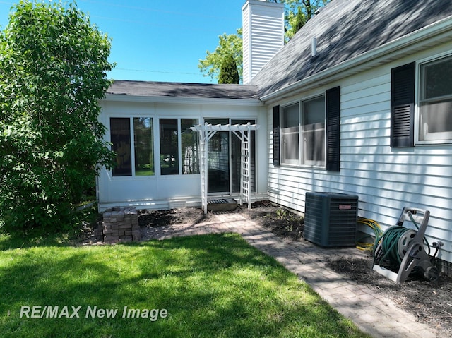 5475 George St, Saginaw, MI 48603 - property entrance featuring central AC unit, a chimney, a yard, and roof with shingles