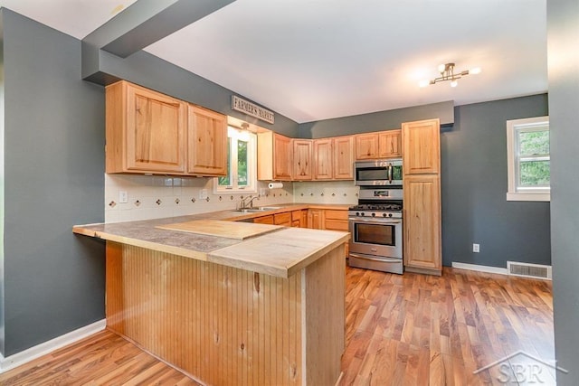 1784 S Badour Rd, Midland, MI 48640 - kitchen featuring appliances with stainless steel finishes, light brown cabinetry, a peninsula, and healthy amount of natural light