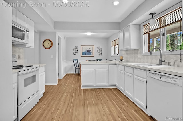 9587 Harmon Ln, South Lyon, MI 48178 - kitchen with white appliances, a sink, light countertops, white cabinets, and a peninsula