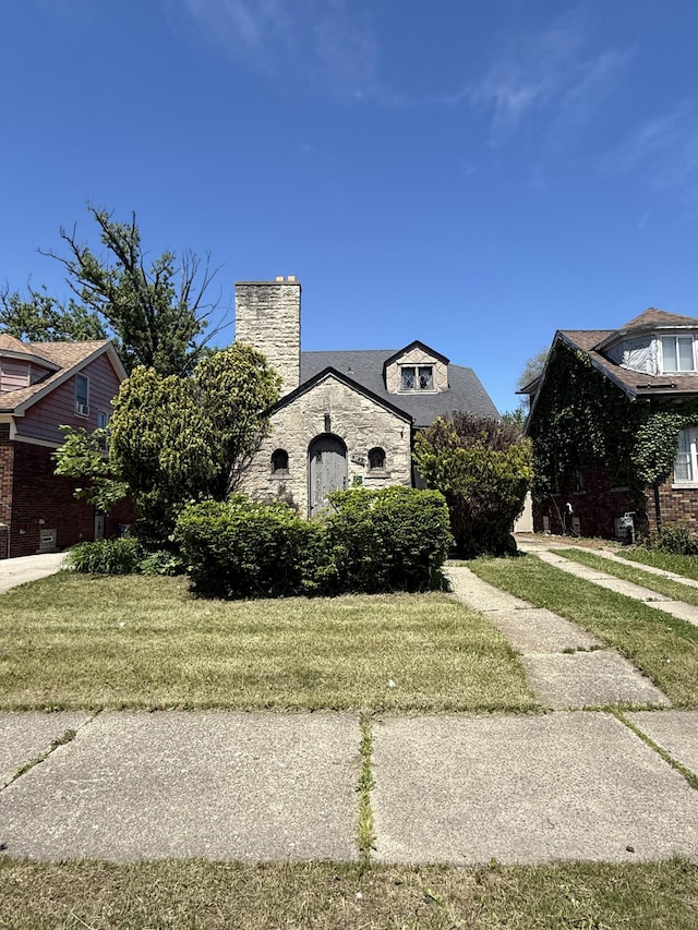 9142 Yorkshire Rd, Detroit, MI 48224 - view of front of house featuring a chimney, a front lawn, and stone siding