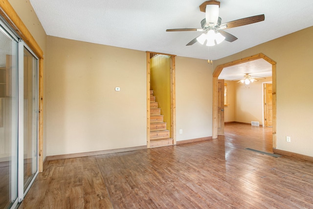 222 Oak St, South Haven, MI 49090 - spare room featuring a ceiling fan, wood finished floors, stairway, arched walkways, and baseboards