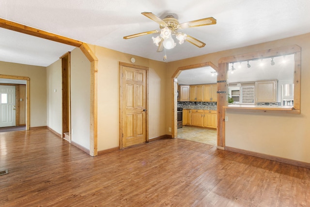 222 Oak St, South Haven, MI 49090 - unfurnished living room with arched walkways, a ceiling fan, light wood finished floors, and baseboards