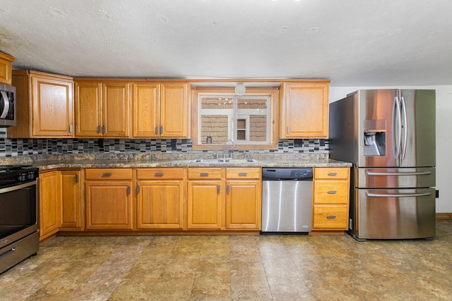 222 Oak St, South Haven, MI 49090 - kitchen with stainless steel appliances, a sink, backsplash, stone counters, and brown cabinetry