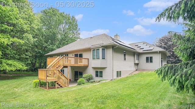 5305 Fern Dr, Fenton, MI 48430 - rear view of house with stairs, a chimney, roof mounted solar panels, a wooden deck, and a yard