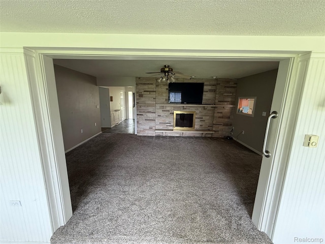 7145 Morrish Rd, Swartz Creek, MI 48473 - unfurnished living room with carpet floors, a fireplace, a ceiling fan, baseboards, and a textured ceiling
