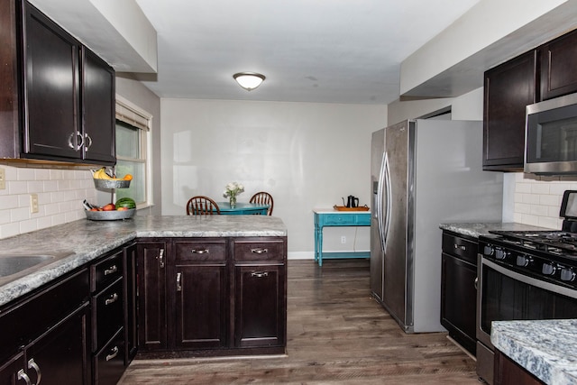 1419 Vassar Dr, Kalamazoo, MI 49001 - kitchen featuring stainless steel appliances, dark wood-style floors, a peninsula, tasteful backsplash, and light countertops