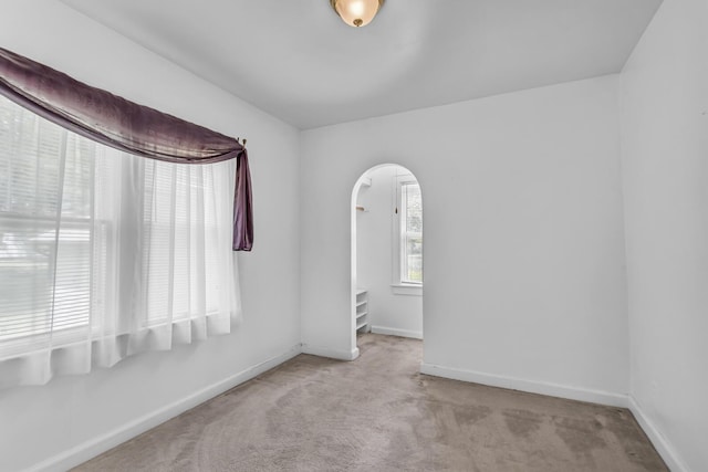 870 Bryant Ave, Jackson, MI 49202 - spare room with arched walkways, carpet flooring, and baseboards