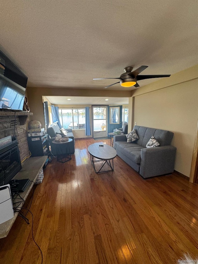 6111 Loud Dr, Oscoda, MI 48750 - living area with a textured ceiling, hardwood / wood-style flooring, ceiling fan, and a fireplace