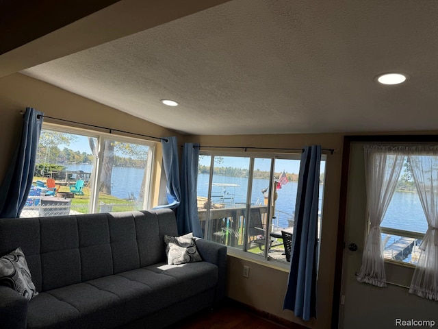 6111 Loud Dr, Oscoda, MI 48750 - living room with healthy amount of natural light, a textured ceiling, recessed lighting, a water view, and dark wood-type flooring