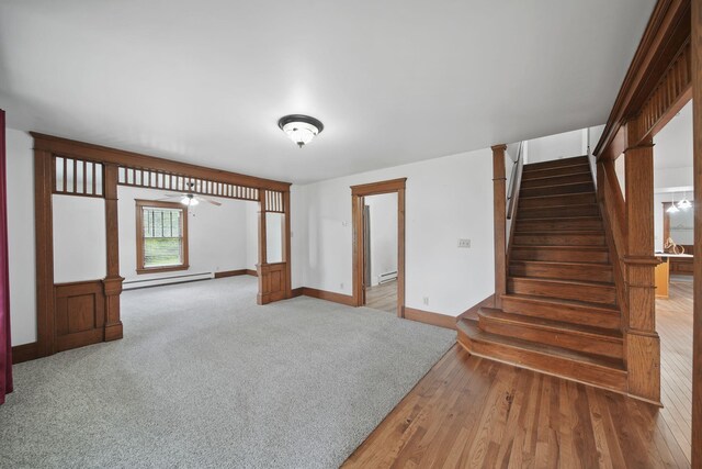 7331 Browns Lake Rd, Jackson, MI 49201 - unfurnished living room with baseboard heating, stairs, baseboards, wood finished floors, and ceiling fan