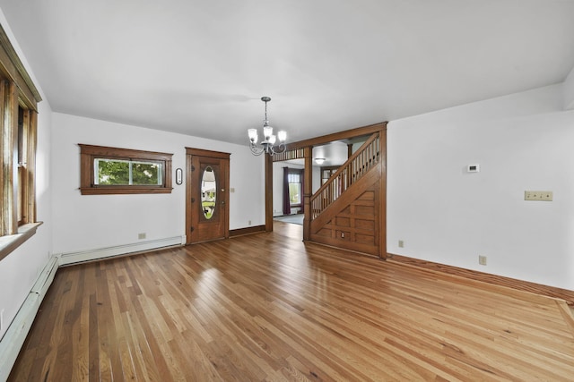 7331 Browns Lake Rd, Jackson, MI 49201 - unfurnished room featuring a chandelier, wood-type flooring, stairway, a baseboard heating unit, and baseboards