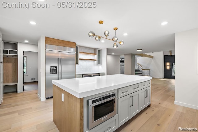 1367 W Long Lake Rd, Bloomfield Hills, MI 48302 - kitchen featuring appliances with stainless steel finishes, a kitchen island, light wood finished floors, light countertops, and recessed lighting