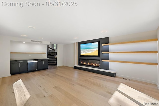 1367 W Long Lake Rd, Bloomfield Hills, MI 48302 - unfurnished living room with stairs, a glass covered fireplace, light wood-style floors, and baseboards