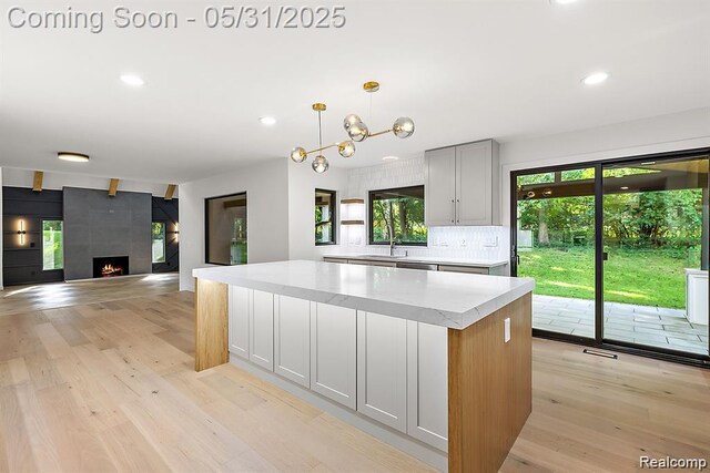 1367 W Long Lake Rd, Bloomfield Hills, MI 48302 - kitchen with a sink, recessed lighting, a kitchen island, light wood-style flooring, and a fireplace